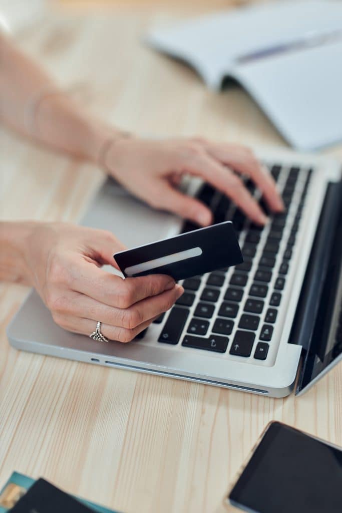 Woman holding credit card and purchasing online with modern laptop.