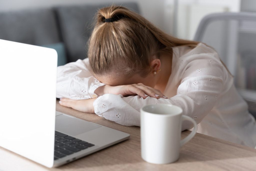 Girl with head on laptop appearing sad.