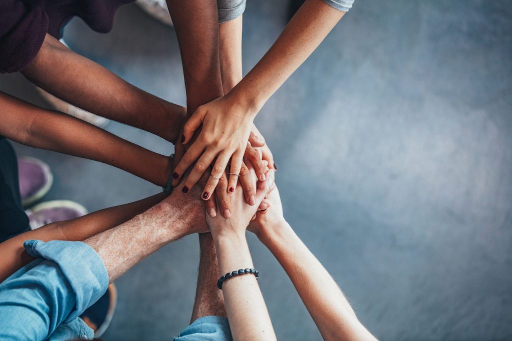 Lots of hands in a huddle representing teamwork