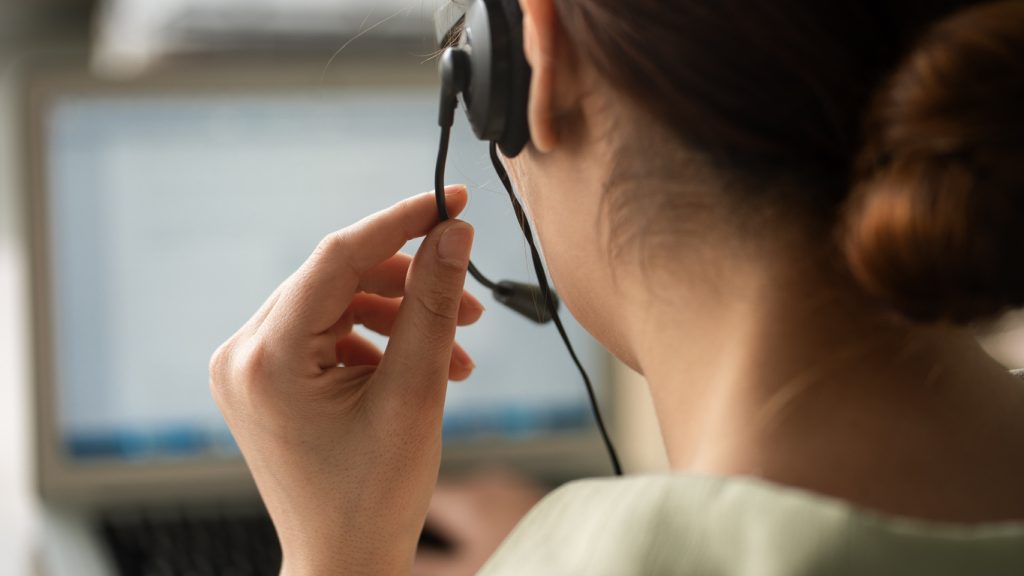 The back of a woman's head with a headset on, working in a call centre