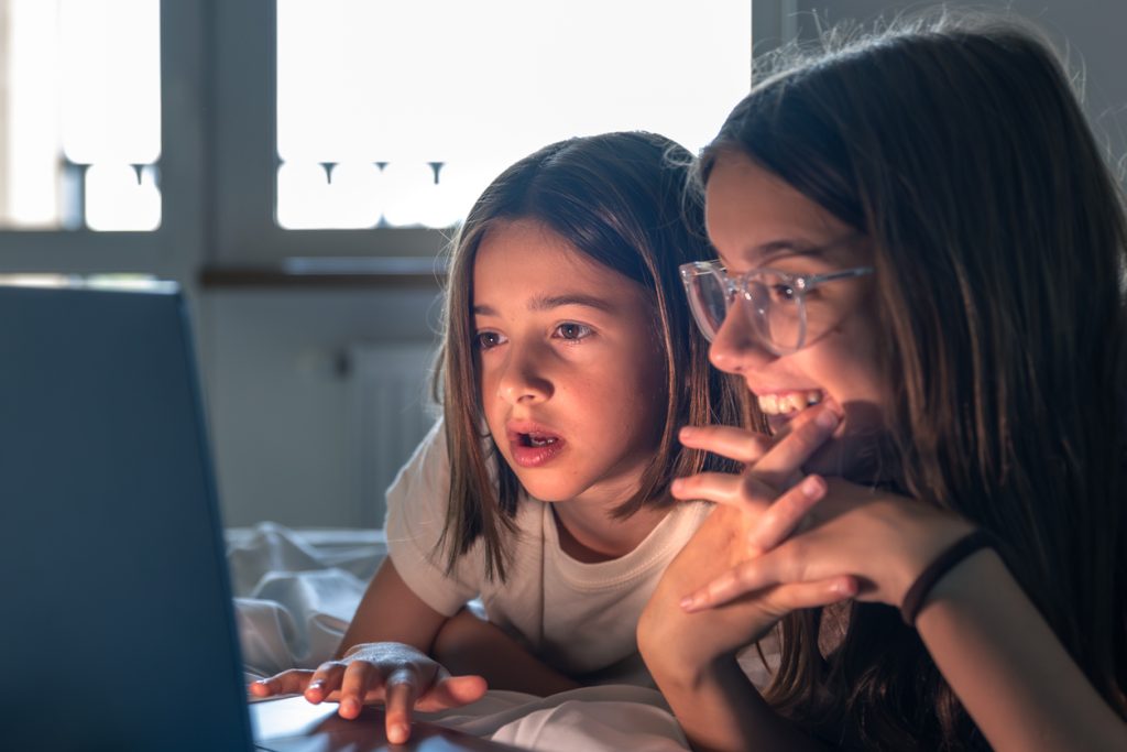 Two girls at a laptop, expectation and joy. Smiling girl watching. Using Laptop, 10-11 Years, 12-13 Years