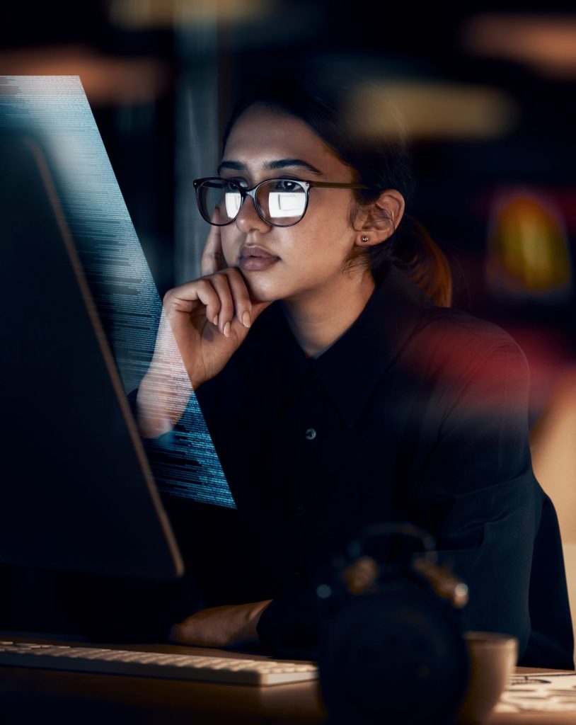 A woman looking at a screen and trying to understand the code. A visual representation of looking behind the firewall.